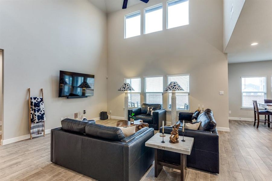 Living room with a towering ceiling, ceiling fan, and light hardwood / wood-style flooring