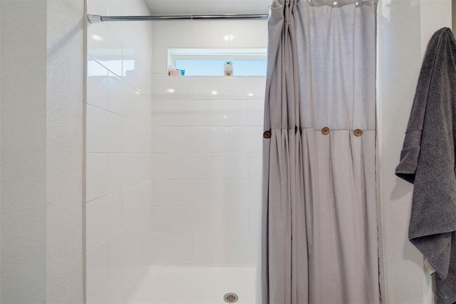Tiled walls and a horizontal transom window define this clean shower space. Tiled walls and a horizontal transom window define this clean shower space.