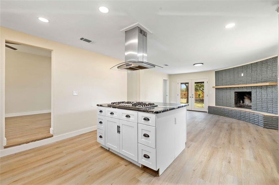 Kitchen with recessed lighting, dark stone counters, light wood-style flooring, white cabinetry, and french doors Kitchen with recessed lighting, dark stone counters, light wood-style flooring, white cabinetry, and french doors