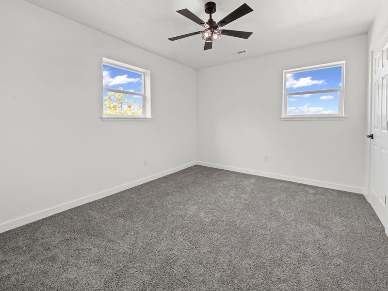 Room featuring gray carpet, white walls, and a black ceiling fan with an integrated light fixture