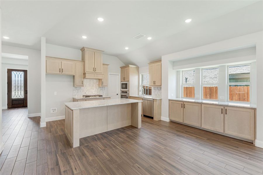 Open kitchen with light wood cabinets, center island, granite countertops, and hardwood floors Open kitchen with light wood cabinets, center island, granite countertops, and hardwood floors