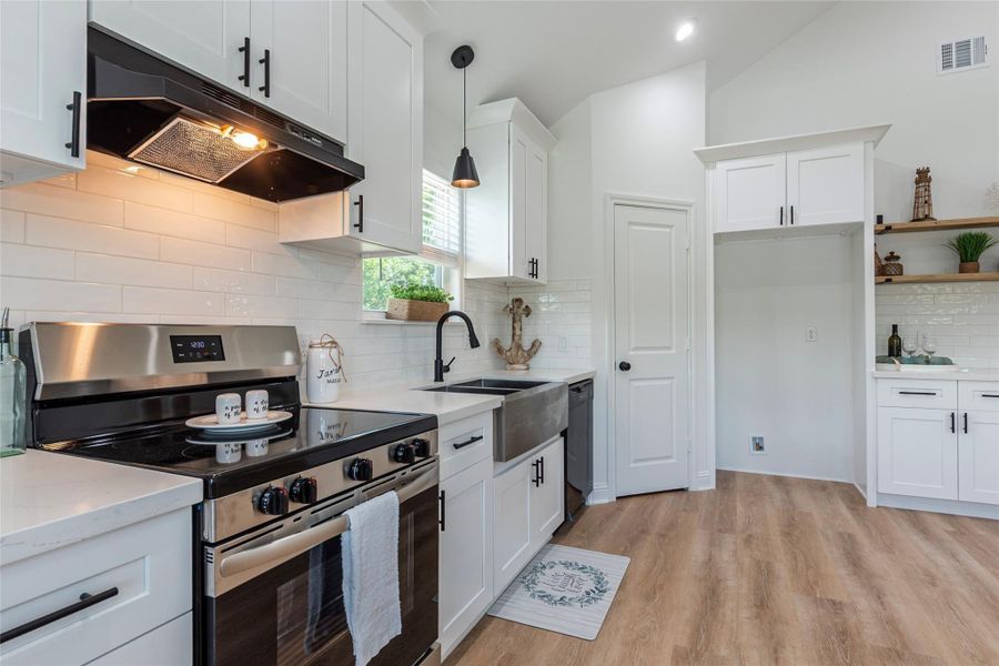 Stainless steel electric range and oven with overhead vent in the large kitchen area.