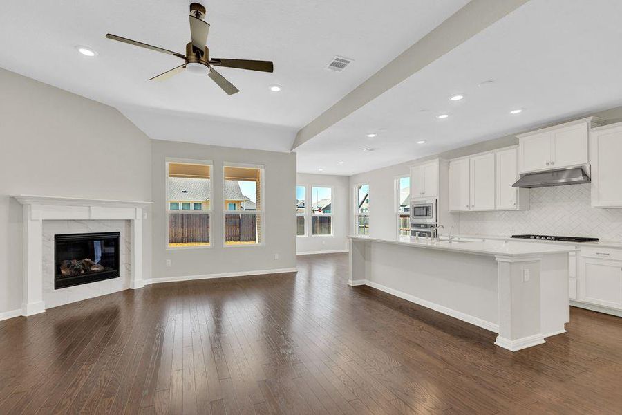 Kitchen featuring open floor plan, an island with sink, decorative backsplash, white cabinetry, and dark wood-style floors Kitchen featuring open floor plan, an island with sink, decorative backsplash, white cabinetry, and dark wood-style floors