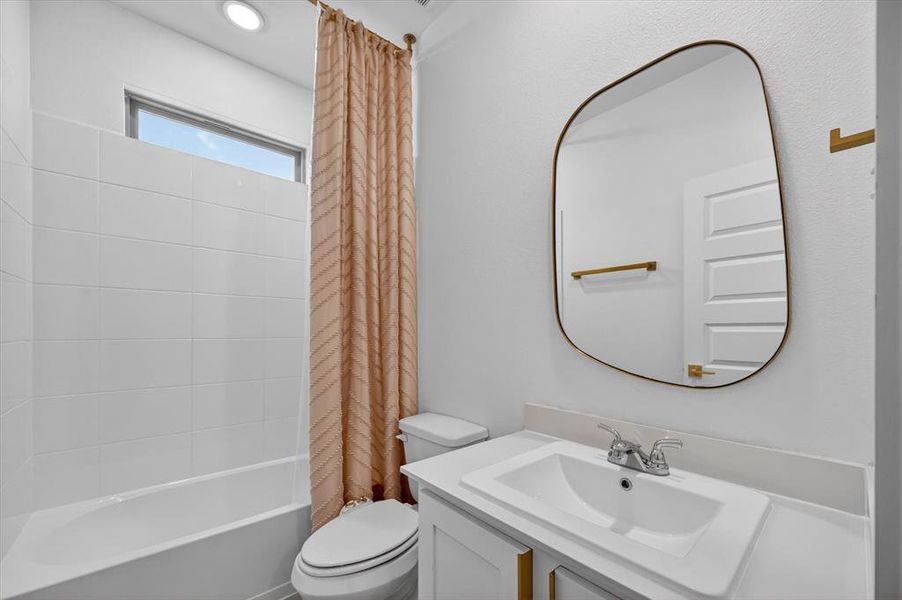 Bathroom featuring a white bathtub with subway tile surround, an overhead transom window, and a vanity with an integrated sink and countertop
