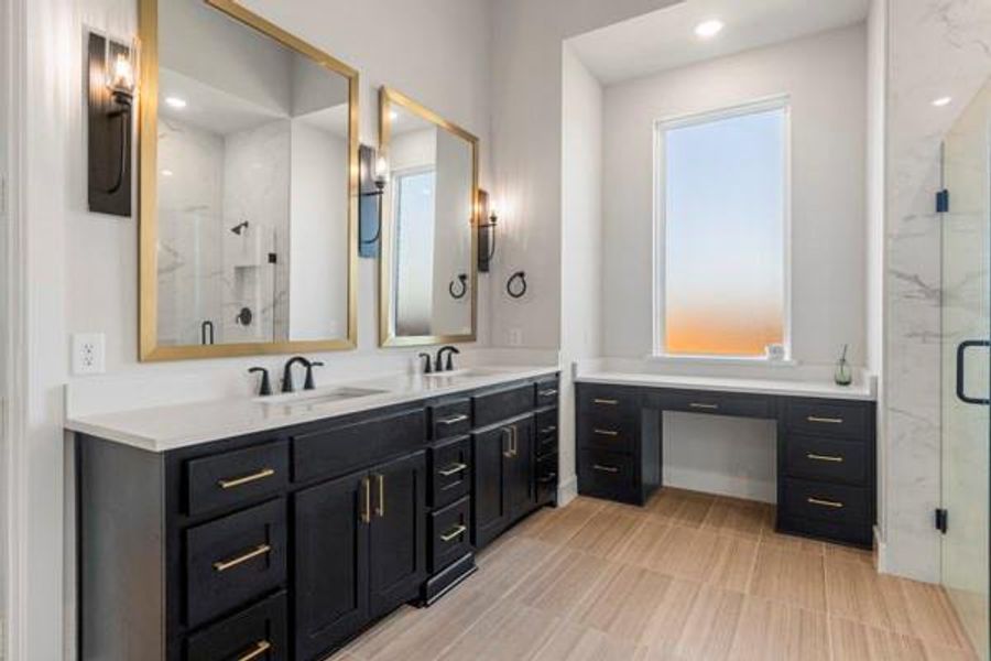 Bathroom with a marble finish shower, double vanity, and recessed lighting