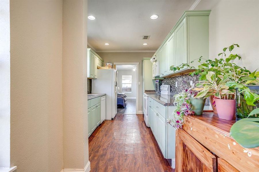 Kitchen featuring white appliances, dark wood-style floors, ornamental molding, recessed lighting, and backsplash