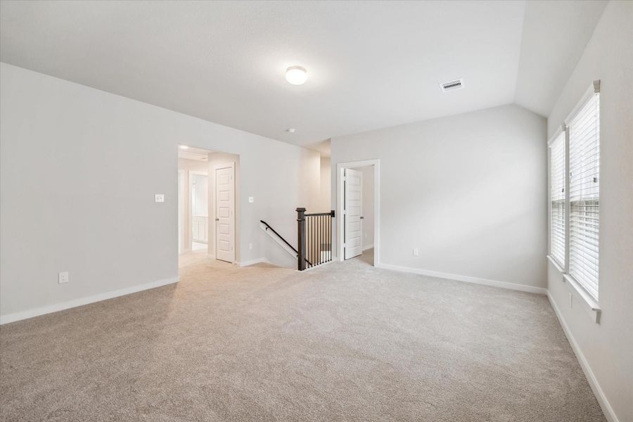 This spacious, carpeted room features neutral walls, ample natural light from double windows, and access to a stairway and multiple doors, offering versatile living options. This spacious, carpeted room features neutral walls, ample natural light from double windows, and access to a stairway and multiple doors, offering versatile living options.