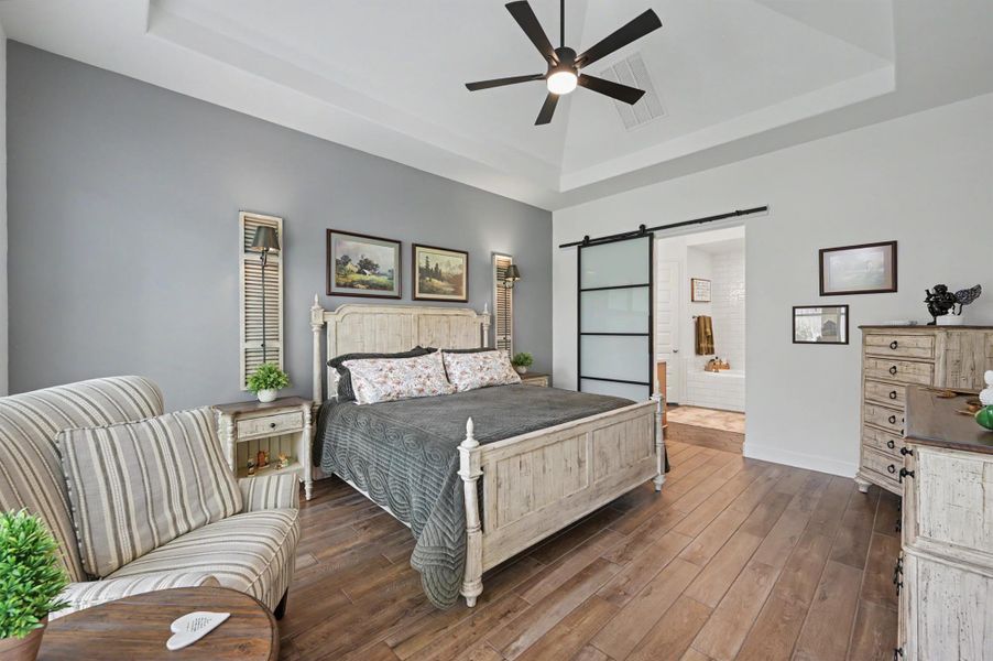 This primary suite is located at the back of the home and has a vaulted, tray ceiling. The room is large enough for king size furniture and a sitting area. The back wall has been painted a light gray and sets the mood for this space. This primary suite is located at the back of the home and has a vaulted, tray ceiling. The room is large enough for king size furniture and a sitting area. The back wall has been painted a light gray and sets the mood for this space.