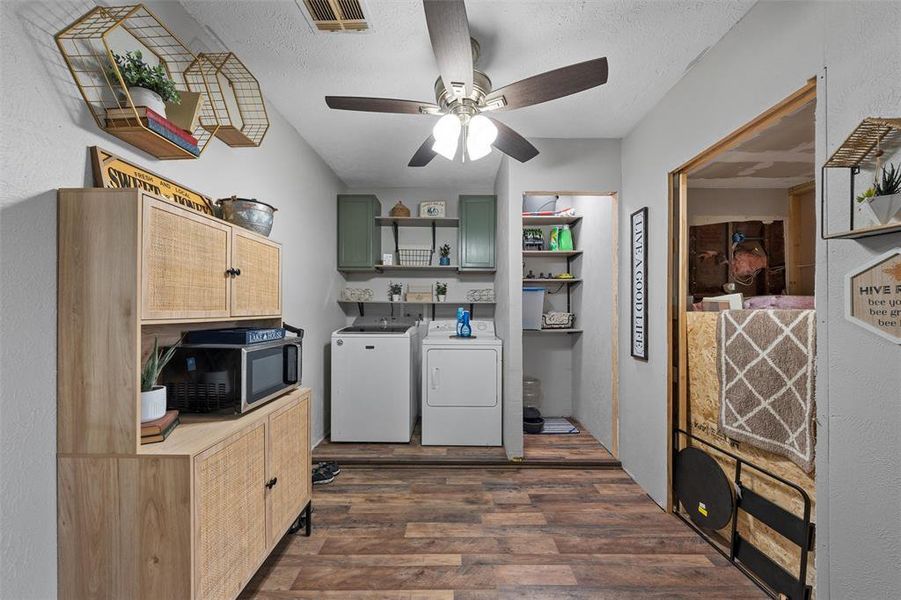Laundry room featuring separate washer and dryer, cabinet space, dark wood-style flooring, a ceiling fan, and a textured ceiling Laundry room featuring separate washer and dryer, cabinet space, dark wood-style flooring, a ceiling fan, and a textured ceiling