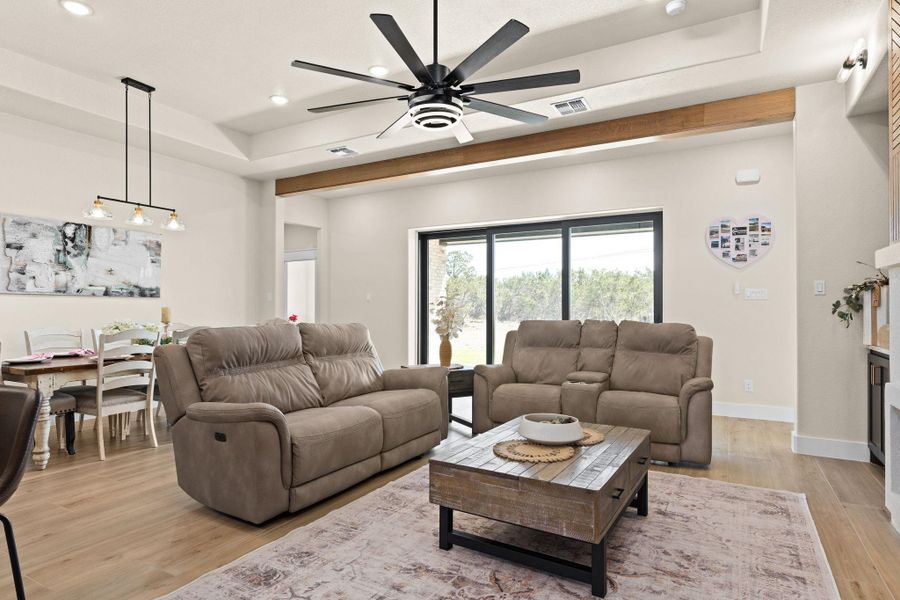 Living area with a tray ceiling, a ceiling fan, recessed lighting, light wood-type flooring, and baseboards Living area with a tray ceiling, a ceiling fan, recessed lighting, light wood-type flooring, and baseboards