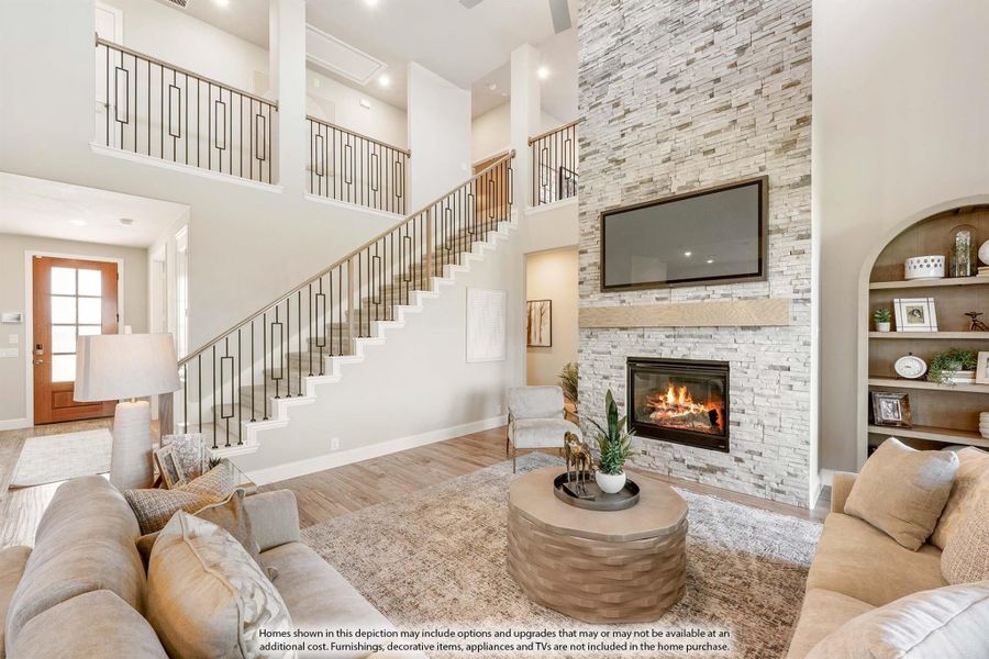 Two-story living room with stone fireplace, open staircase, and built-in shelving Two-story living room with stone fireplace, open staircase, and built-in shelving