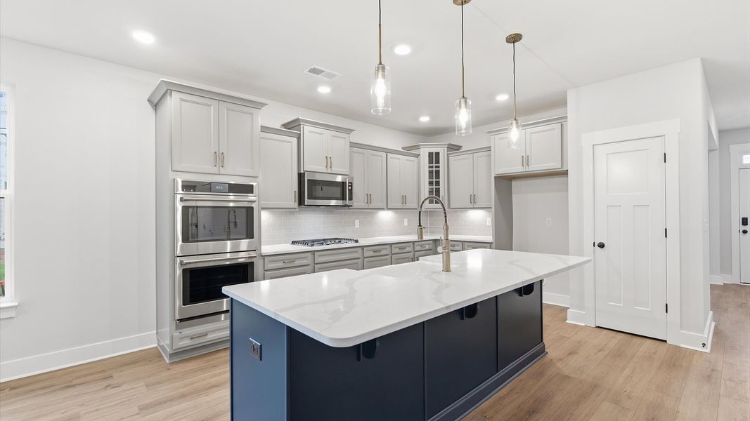 Accomplished kitchen design featuring pendant lighting above a statement island for both prep and gathering at Woodglen Accomplished kitchen design featuring pendant lighting above a statement island for both prep and gathering at Woodglen