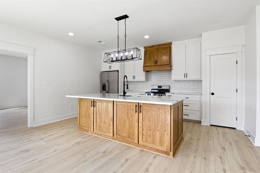 Kitchen with brown cabinets, white cabinets, hanging light fixtures, tasteful backsplash, and recessed lighting