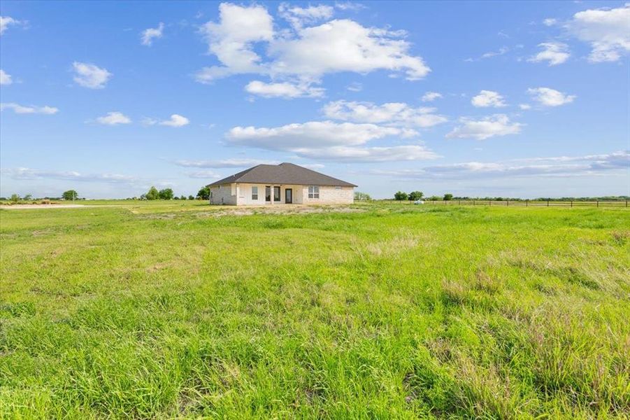 View of yard with fence and a rural view