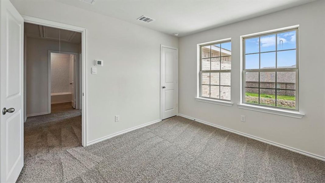 Unfurnished bedroom with attic access and light carpet