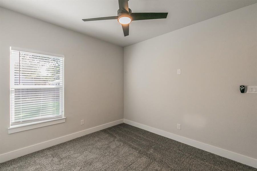 Spare room featuring dark carpet and ceiling fan