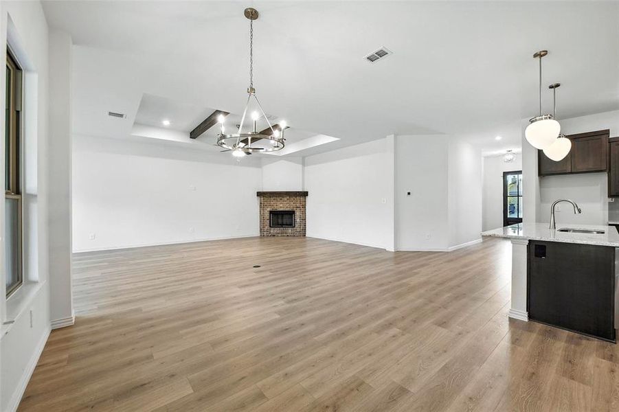 Unfurnished living room featuring a chandelier, light wood finished floors, recessed lighting, and a fireplace