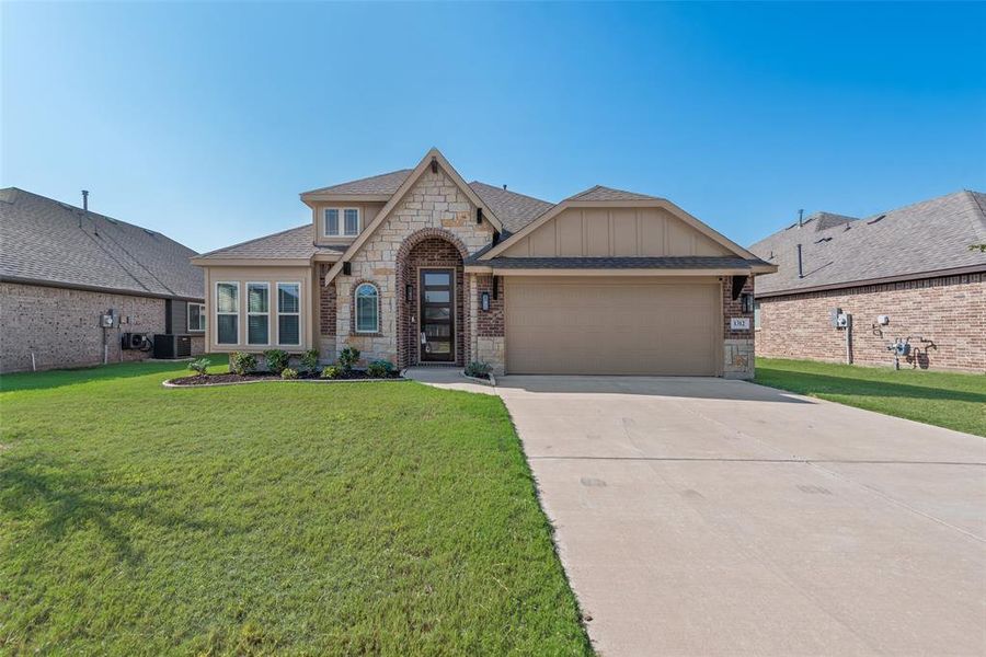 View of front of house with stone siding, a shingled roof, driveway, a front lawn, and an attached garage View of front of house with stone siding, a shingled roof, driveway, a front lawn, and an attached garage
