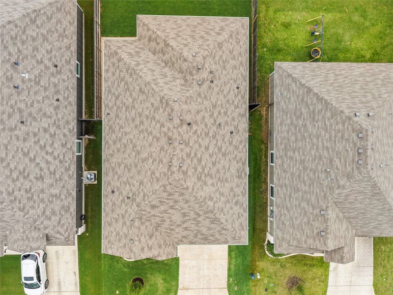 An aerial perspective reveals the well-maintained shingle roofs and surrounding green lawns of several residential properties. An aerial perspective reveals the well-maintained shingle roofs and surrounding green lawns of several residential properties.