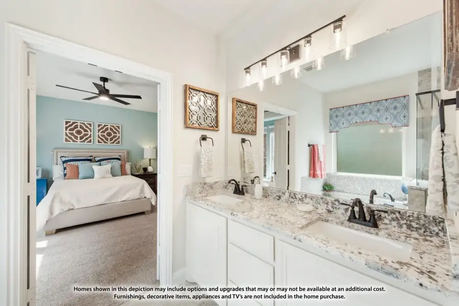 Ensuite bathroom with double vanity and granite countertops, open to master bedroom with ceiling fan
