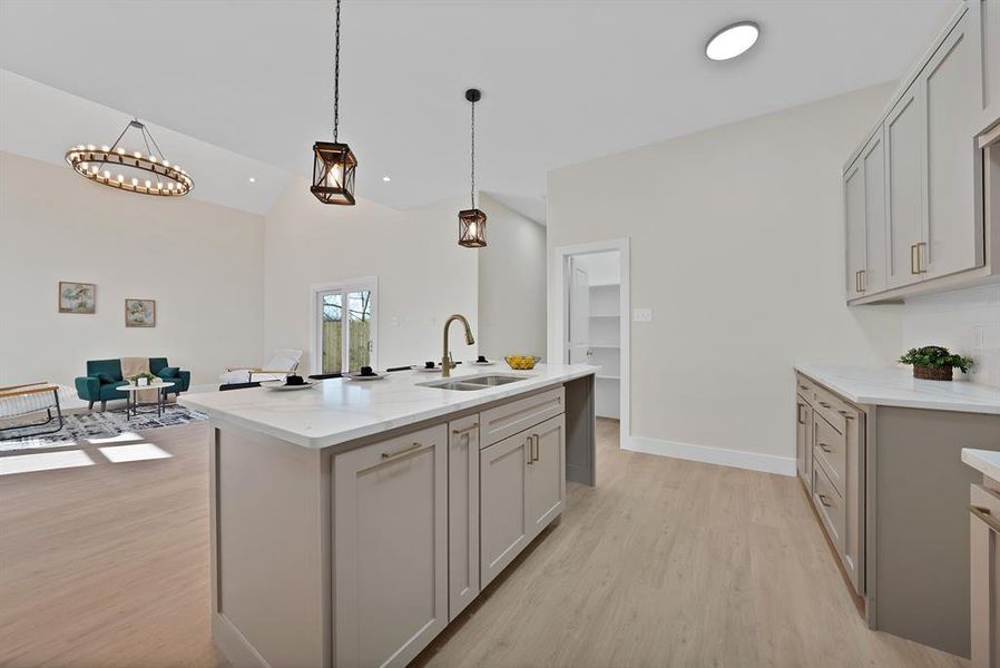Kitchen featuring hanging light fixtures, light wood-style floors, gray cabinetry, and lofted ceiling