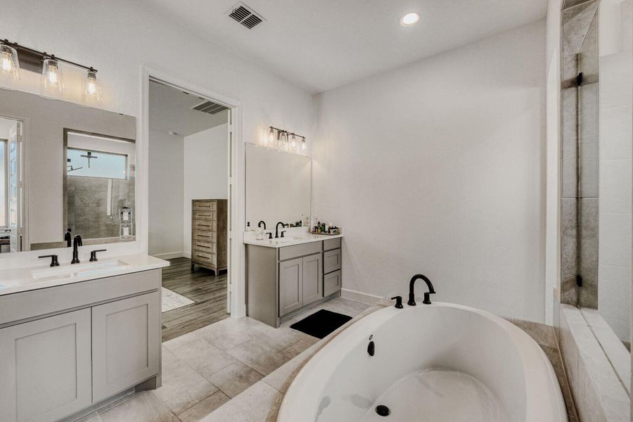 Bathroom with a shower stall, two vanities, a bath, recessed lighting, and light tile patterned floors