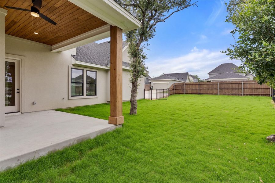 An inviting covered patio transitions to a spacious, well-maintained lawn, perfect for outdoor activities.