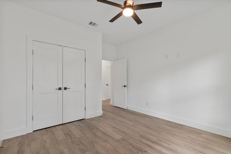 Unfurnished bedroom with light wood-style flooring, a closet, and a ceiling fan Unfurnished bedroom with light wood-style flooring, a closet, and a ceiling fan