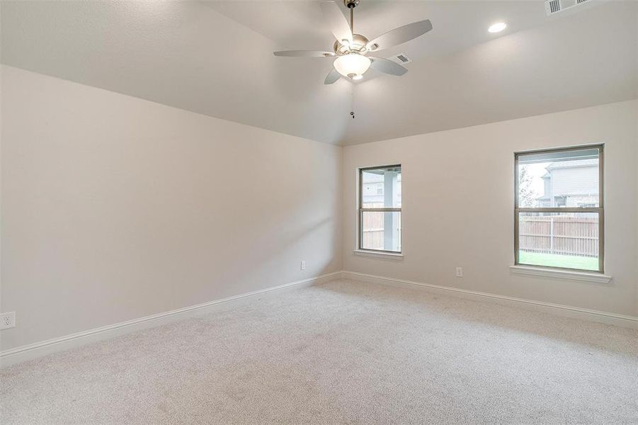 Spare room with vaulted ceiling, ceiling fan, and carpet