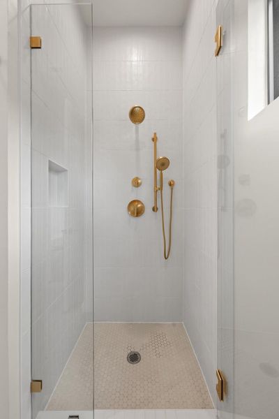 A sleek shower enclosure features a combination of rain shower and handheld fixtures with a practical wall niche. A sleek shower enclosure features a combination of rain shower and handheld fixtures with a practical wall niche.
