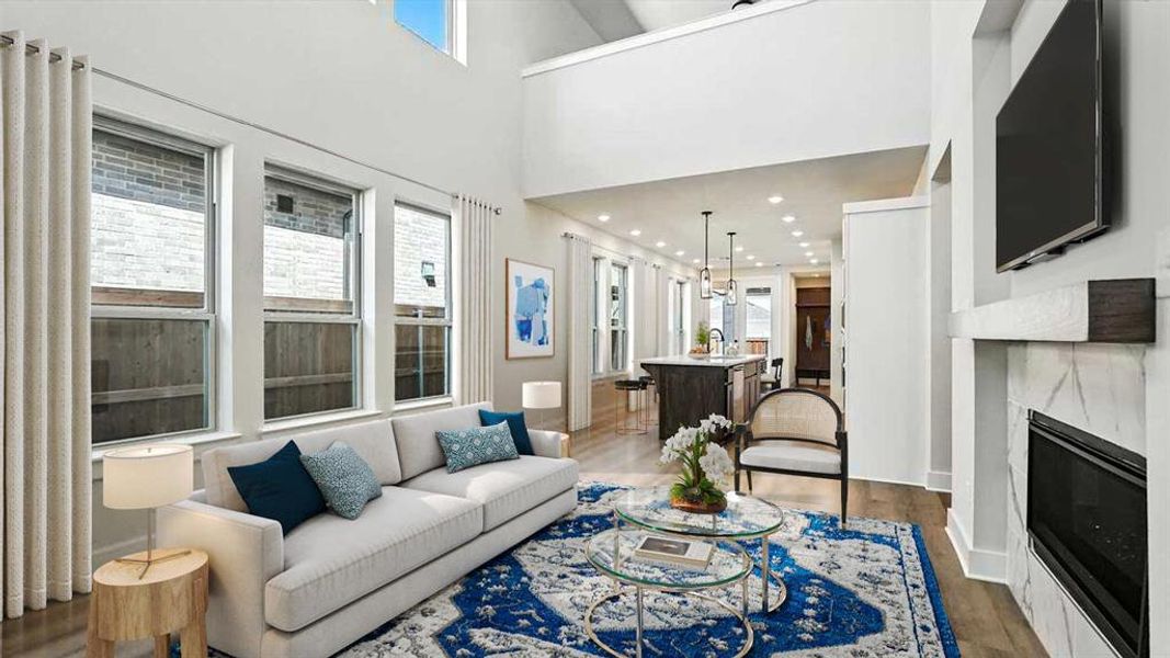 Living area with wood finished floors, a premium fireplace, recessed lighting, and a high ceiling Living area with wood finished floors, a premium fireplace, recessed lighting, and a high ceiling
