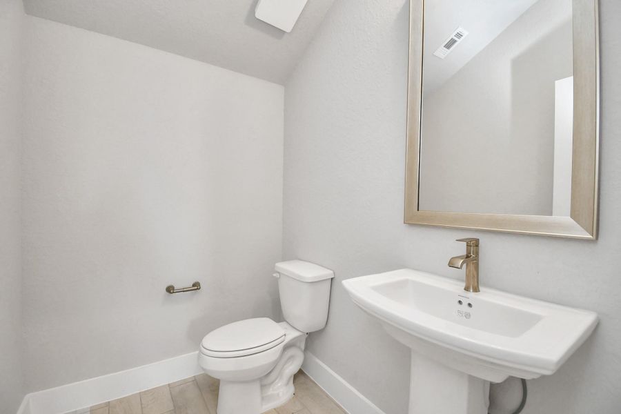 This half bathroom features a stylish pedestal sink, modern hardware, and bright recessed lighting, creating a sleek and inviting space. Sample photo of completed home with similar floor plan. Actual colors and selections may vary. This half bathroom features a stylish pedestal sink, modern hardware, and bright recessed lighting, creating a sleek and inviting space. Sample photo of completed home with similar floor plan. Actual colors and selections may vary.