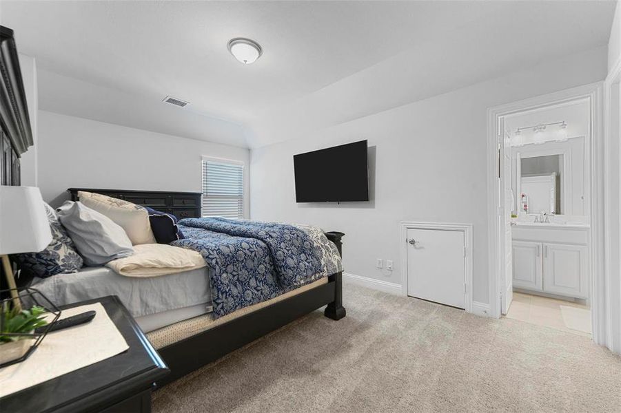 Bedroom featuring light colored carpet and ensuite bath