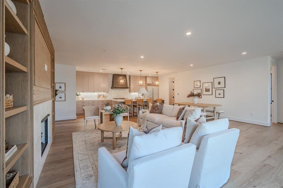 Living room featuring light wood-style floors, recessed lighting, and a large fireplace Living room featuring light wood-style floors, recessed lighting, and a large fireplace