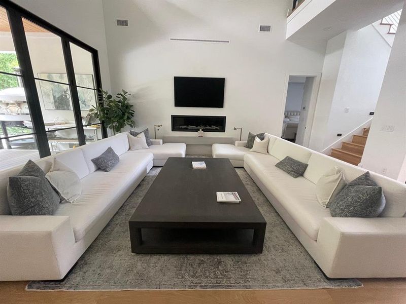 Living room with a fireplace, hardwood / wood-style floors, and a high ceiling