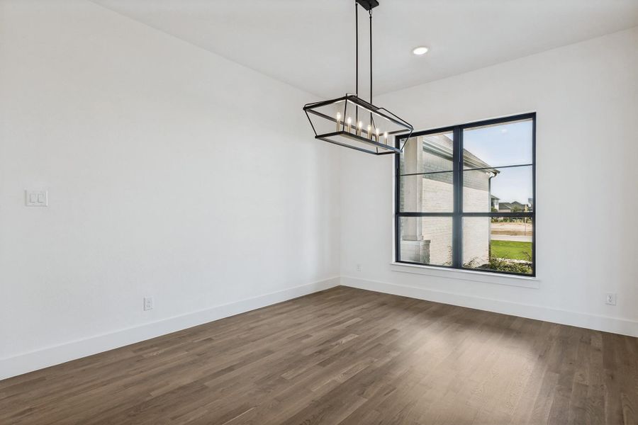 Rich hardwood floors and a modern linear fixture anchor this light-filled dining space.
