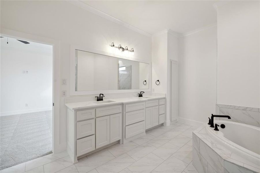 Bathroom with ceiling fan, tiled tub, crown molding, and vanity