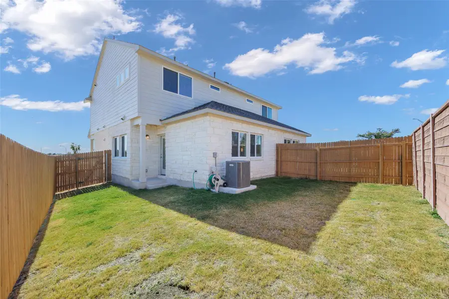 Back of house featuring a fenced backyard and stone siding Back of house featuring a fenced backyard and stone siding