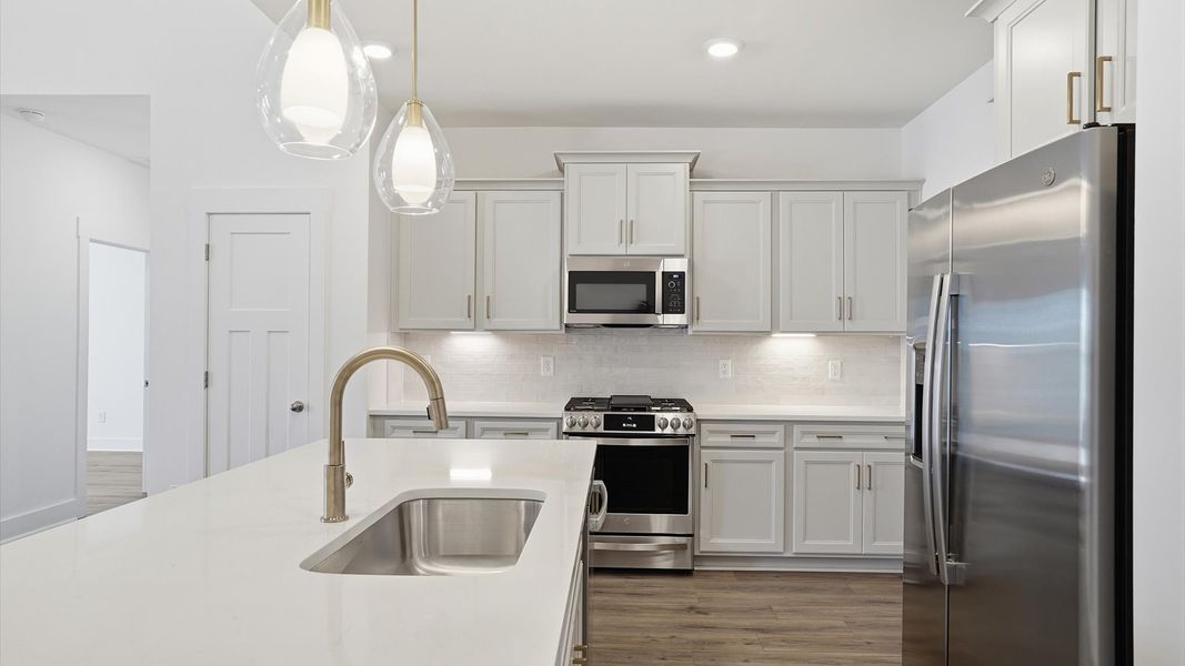Tasteful kitchen with a streamlined island and modern finishes in a first-class DRB Homes design Tasteful kitchen with a streamlined island and modern finishes in a first-class DRB Homes design
