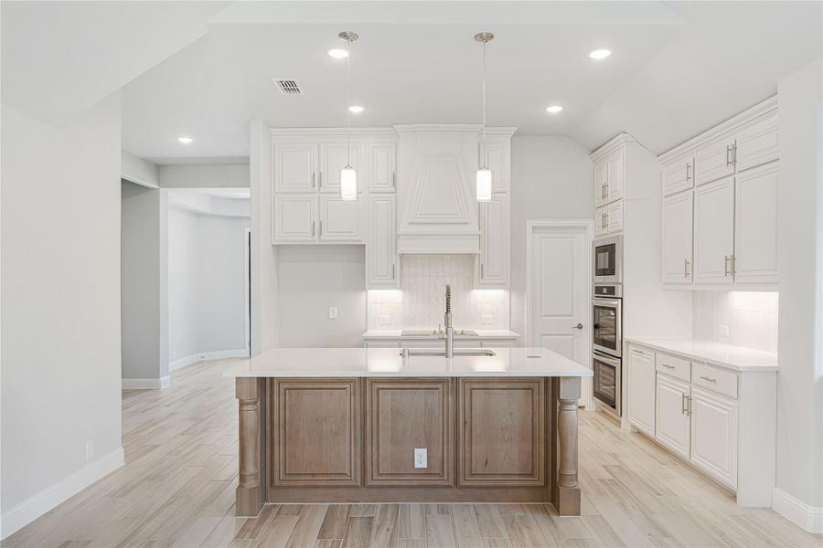 Kitchen with white cabinets, wood island, pendant lights, and double wall ovens on light tile floors