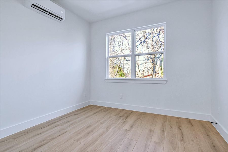 Unfurnished room with baseboards, light wood finished floors, and a wall mounted AC