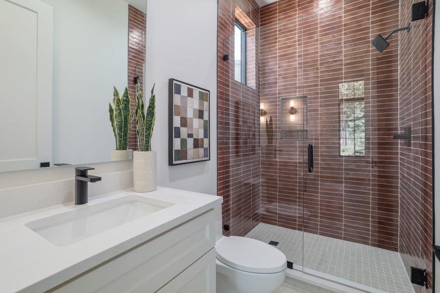 Contemporary bathroom featuring a spacious glass-enclosed shower with horizontal brick-patterned tile, a built-in shower niche with sconce lighting, and a rainfall showerhead