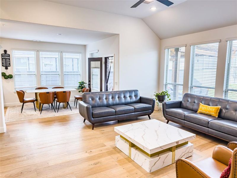 Living room with light wood finished floors, ceiling fan, recessed lighting, and vaulted ceiling