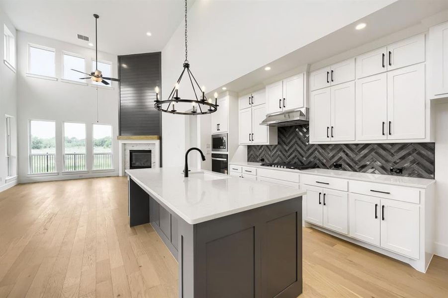 Open-concept living space featuring a modern kitchen island with a white countertop and dark cabinetry
