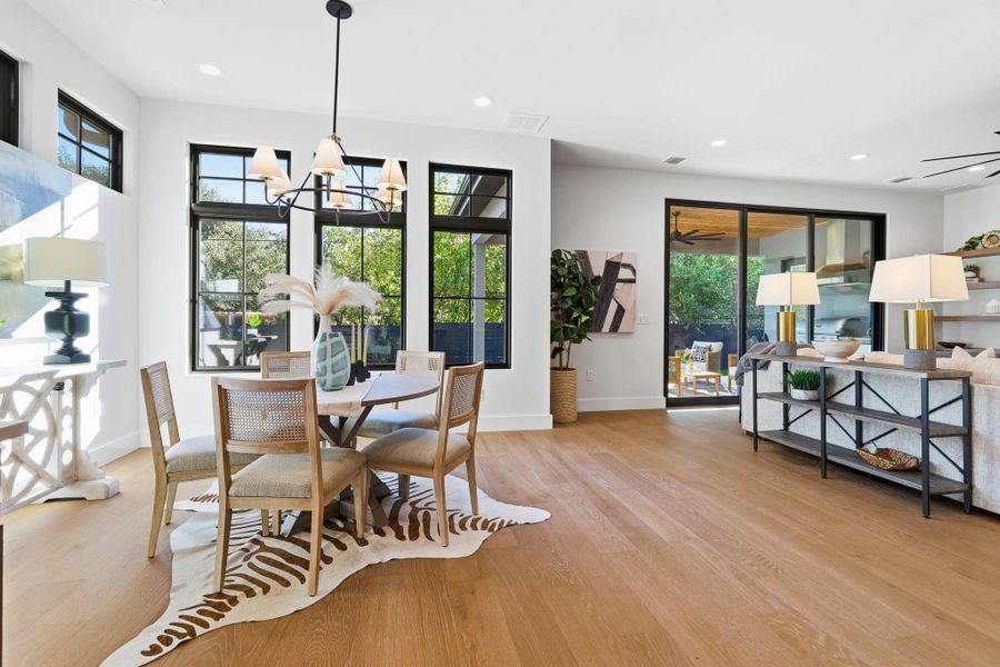 Dining space featuring light wood finished floors, healthy amount of natural light, recessed lighting, and a chandelier