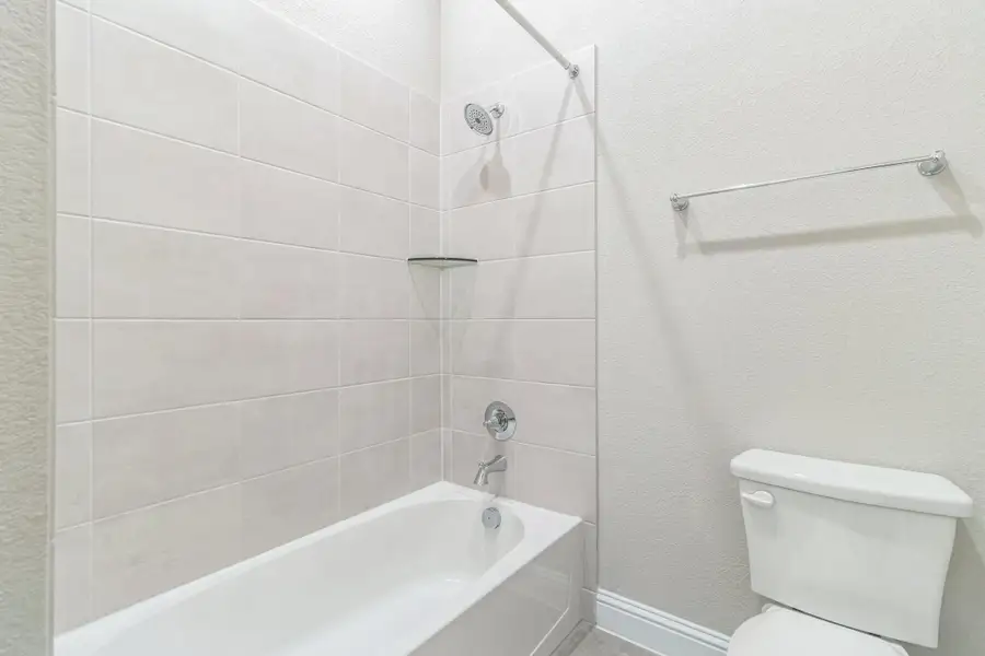 Bathroom with baseboards, washtub / shower combination, and toilet