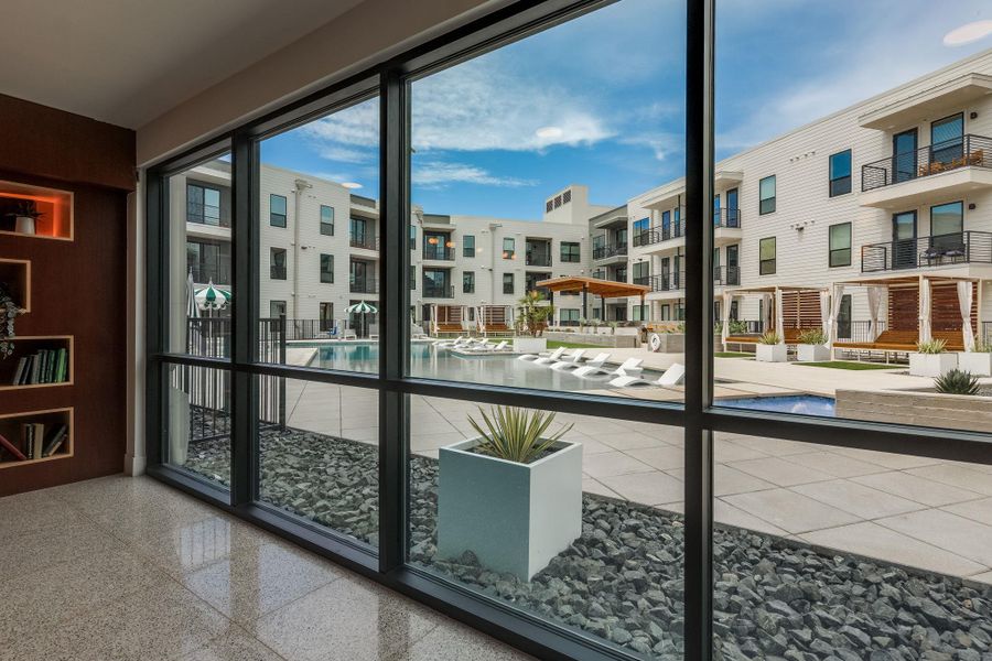 Expansive windows reveal a view of the community pool and surrounding buildings, featuring balconies and outdoor seating areas