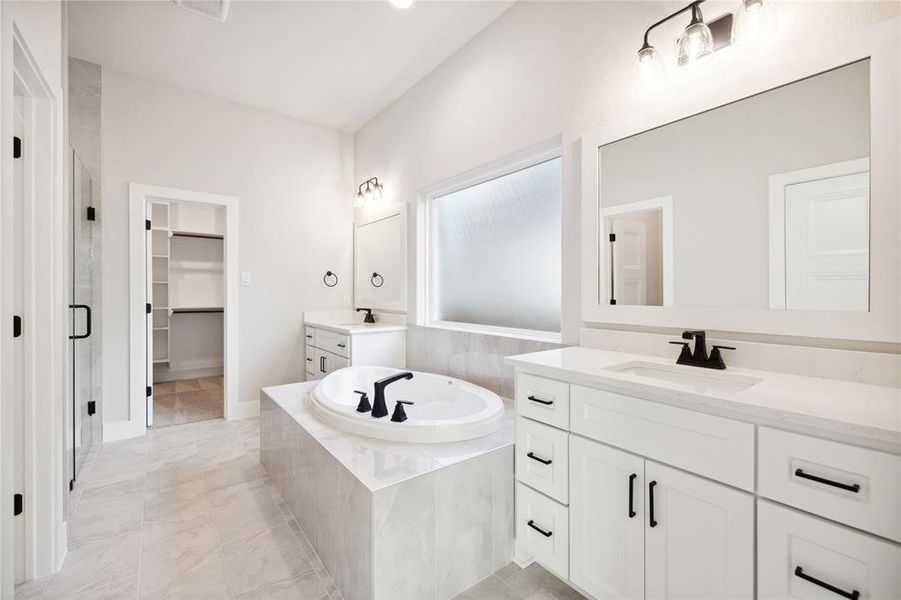 Bathroom featuring tile patterned flooring, shower with separate bathtub, and vanity