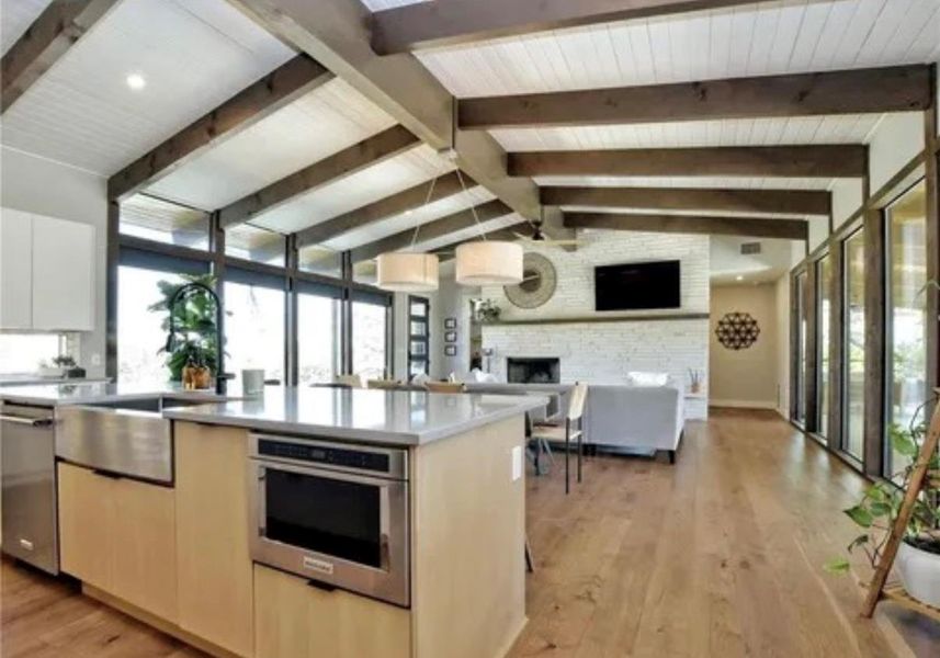 Kitchen with light wood finished floors, open floor plan, stainless steel appliances, modern cabinets, and a stone fireplace Kitchen with light wood finished floors, open floor plan, stainless steel appliances, modern cabinets, and a stone fireplace