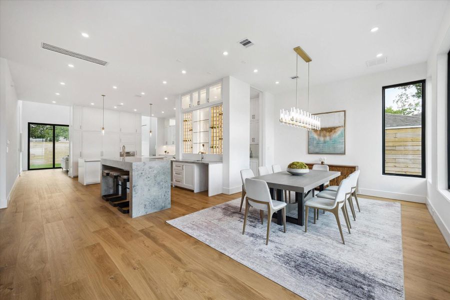 Formal dining with statement lighting, wood floors, and garden views. Formal dining with statement lighting, wood floors, and garden views.